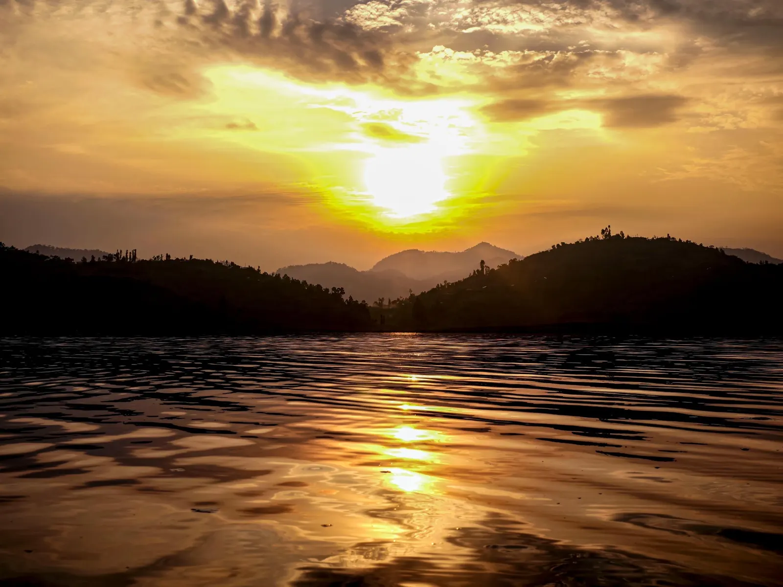 Golden sunset reflected across a lake beneath rolling hills