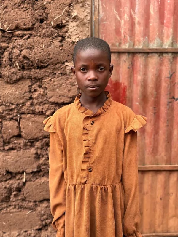 A child standing beside a doorway in a yellow dress