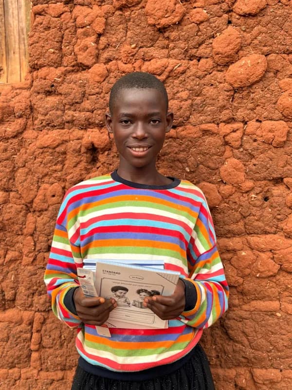 A young person in a striped top holding learning materials