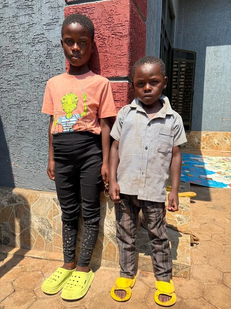 Two children standing together by the entrance of a home